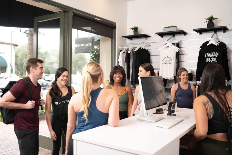 Pure Barre - Group gathering and talking at the Pure Barre check-in counter.