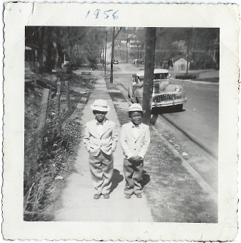 photo of two little boys in suits and hats on street with car behind them, labeled 1956