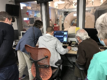 men and women clustered around monitor displaying micographic image of old book spine